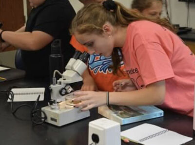 HRA senior Carys Casper '26 teaches summer campers at VIMS how to examine samples under the microscope