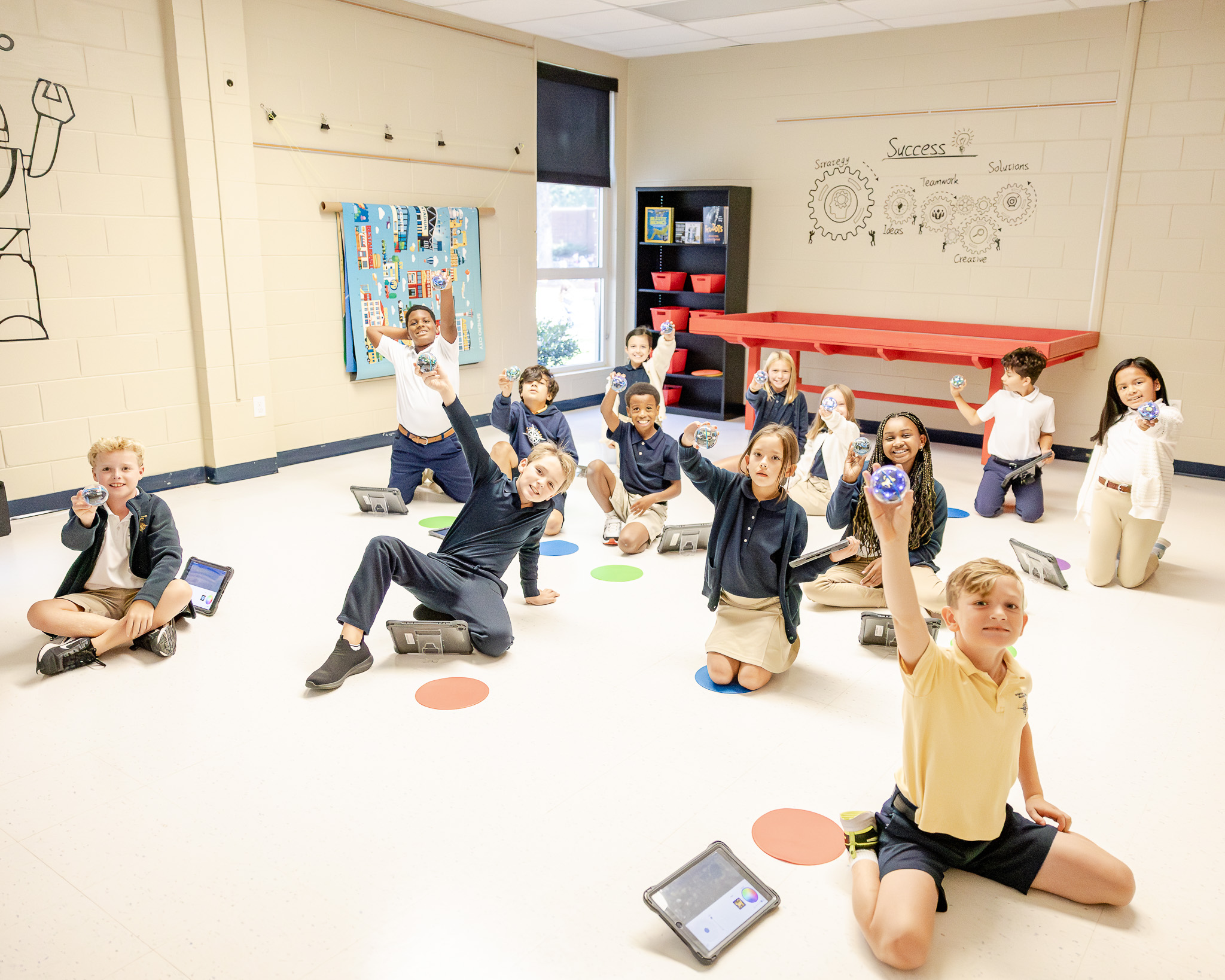Fourth graders hold up their Sphero robots in the Lower School Robotics Room at Hampton Roads Academy
